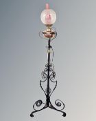 An antique wrought iron rise and fall standard oil lamp with copper reservoir, chimney and shade.