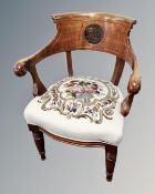 An oak elbow chair with tapestry embroidered seat and carved back.
