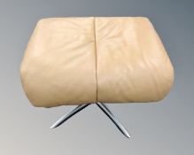 A tan leather footstool on four way chrome pedestal.