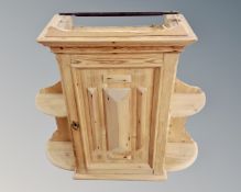 A pine single door wall cabinet, with flanking shelves.