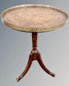 A stained beech wood circular pedestal wine table with leather inset panel and brass gallery