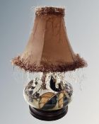 A Moorcroft table lamp decorated with berries on wooden base with tasseled shade