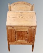 An antique pine fitted writing bureau with cupboard beneath