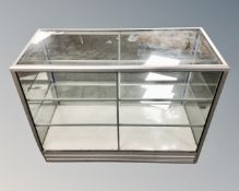 A metal framed shop display cabinet with sliding doors, two shelves,