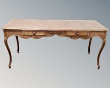 A carved oak two drawer library table on cabriole legs with tooled leather inset panel