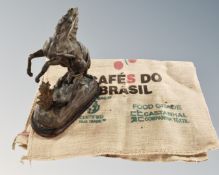 An antique spelter figure of a man with rearing horse together with a Hessian coffee sack