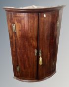 A George III mahogany double door bowfront corner cabinet