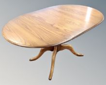 An Ercol elm and beech oval extending table with leaf and set of four swan-backed chairs,