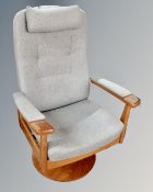 A Scandinavian revolving teak framed armchair upholstered in blue fabric.