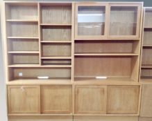 A two section light oak storage unit with sliding door base and cupboard doors above.