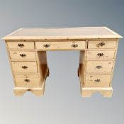An Edwardian pine nine drawer twin pedestal desk with leather panel,