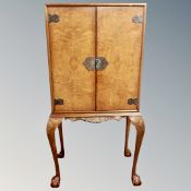 A burr walnut double door cocktail cabinet on raised legs,