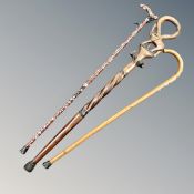 A carved hardwood African style walking stick together with a further walking stick bearing badges