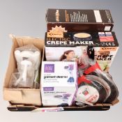 A box containing a steam cleaner, two frying pans, electric crepe maker.