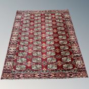 A machined rug of Bokhara design, with repeat gul motif on claret ground, 194cm by 162cm.