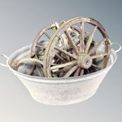 A vintage galvanized metal twin handle wash tub together with three antique cart wheels.