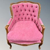 A continental carved beech framed armchair upholstered in a vivid pink buttoned back fabric.