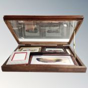 A glazed mahogany tabletop cabinet containing hand painted feathers, tourist items in cases etc.