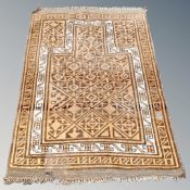 An antique Afghan prayer rug, circa 1900, with cream Mihrab on brown geometric central field,