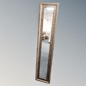 A contemporary 4' by 1' gold frame hall mirror.