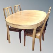 A 20th century Nathan teak oval extending dining table with four matching high backed chairs
