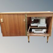 A Singer electric sewing machine in teak cabinet