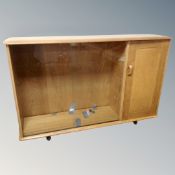 An Ercol elm and beech double door sliding glass door bookcase fitted with cupboard