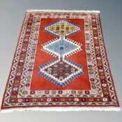 A Caucasian design rug with three geometric serrated medallions on red ground,