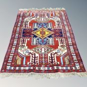 A Caucasian design rug with polychrome geometric motif on red ground,