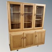 An Ercol Windsor elm and beech triple door glazed bookcase fitted with cupboards beneath
