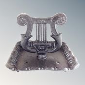 A cast iron lyre boot scraper.