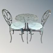 A cast aluminium patio table and two chairs