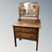 An Edwardian oak two drawer dressing chest on raised legs