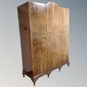 A walnut triple door wardrobe fitted with shelves