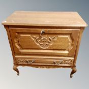 A Continental oak fall front cabinet fitted with a drawer on cabriole legs.