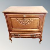 A Continental oak fall front cabinet fitted with a drawer on cabriole legs.