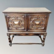 An antique oak double panel door cabinet on stand.