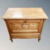 A Continental oak fall front cabinet fitted with a drawer on cabriole legs.