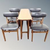 A teak drop leaf table together with a set of four black vinyl dining chairs