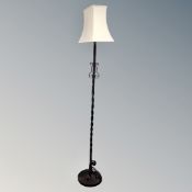 A wrought iron standard lamp with shade