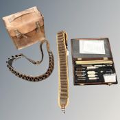 Two leather shotgun cartridge belts together with a cased gun cleaning kit and a brown leather case