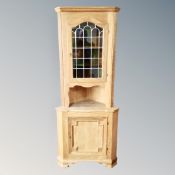 A light oak glazed corner cabinet