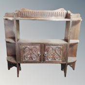 An Edwardian carved beech double door wall shelf