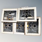 A box containing five Victorian stained glass leaded windows in frames.