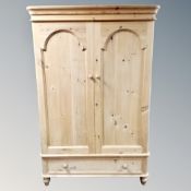 A pine double door wardrobe fitted with a drawer