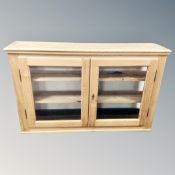 An antique pine double door glazed wall cabinet