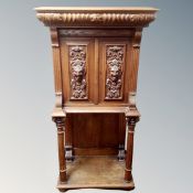 An early 20th century carved oak double door cabinet fitted a drawer on raised pillar legs