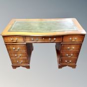A Georgian style serpentine fronted writing desk fitted with nine drawers and green leather panel