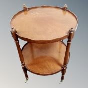 A circular mahogany two tier trolley table on castors