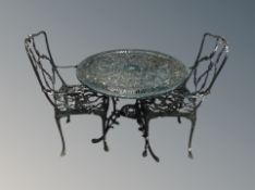 A painted wrought metal circular garden table together with two armchairs